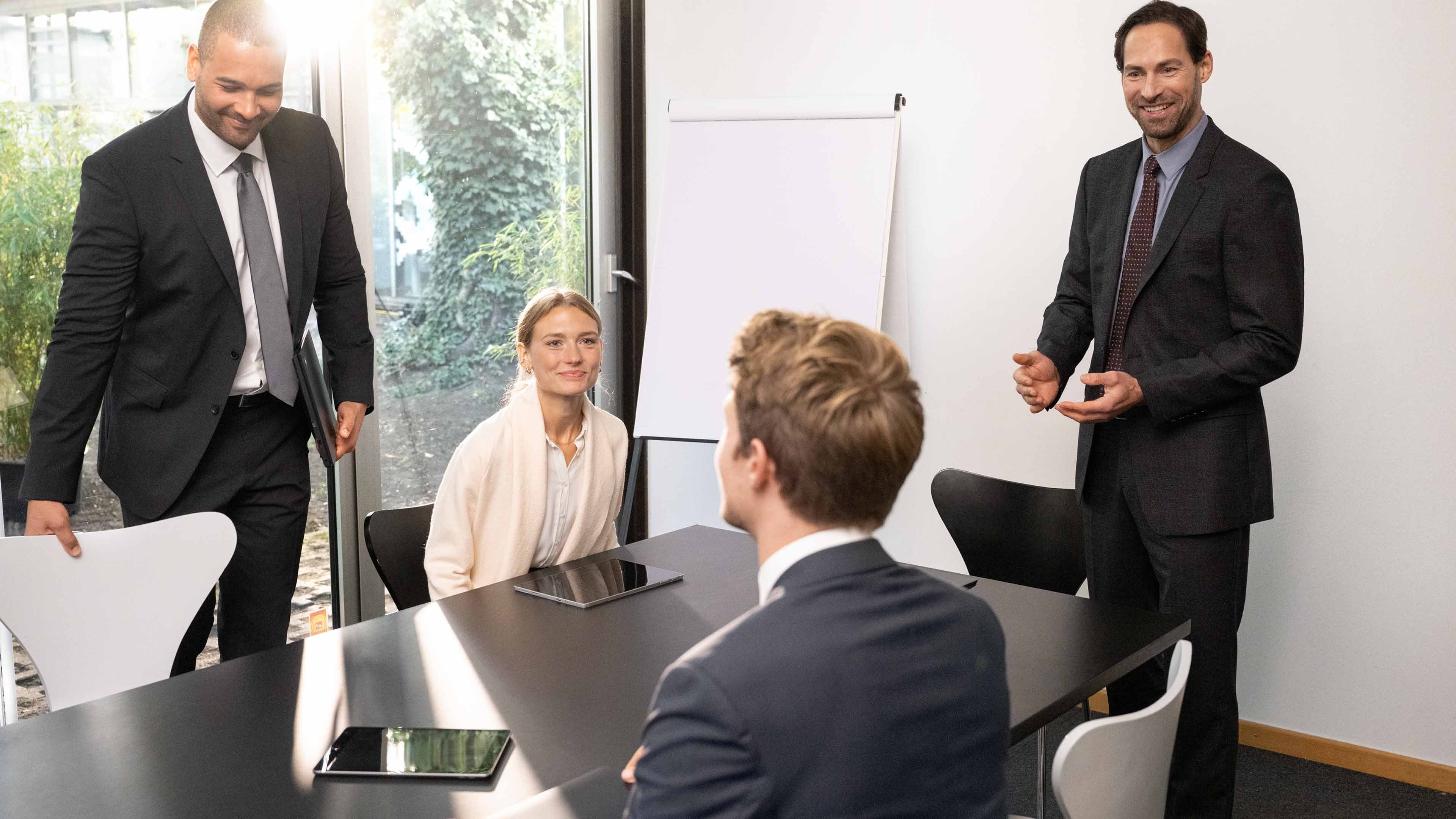 Four people are conversing with each other in a meeting room.