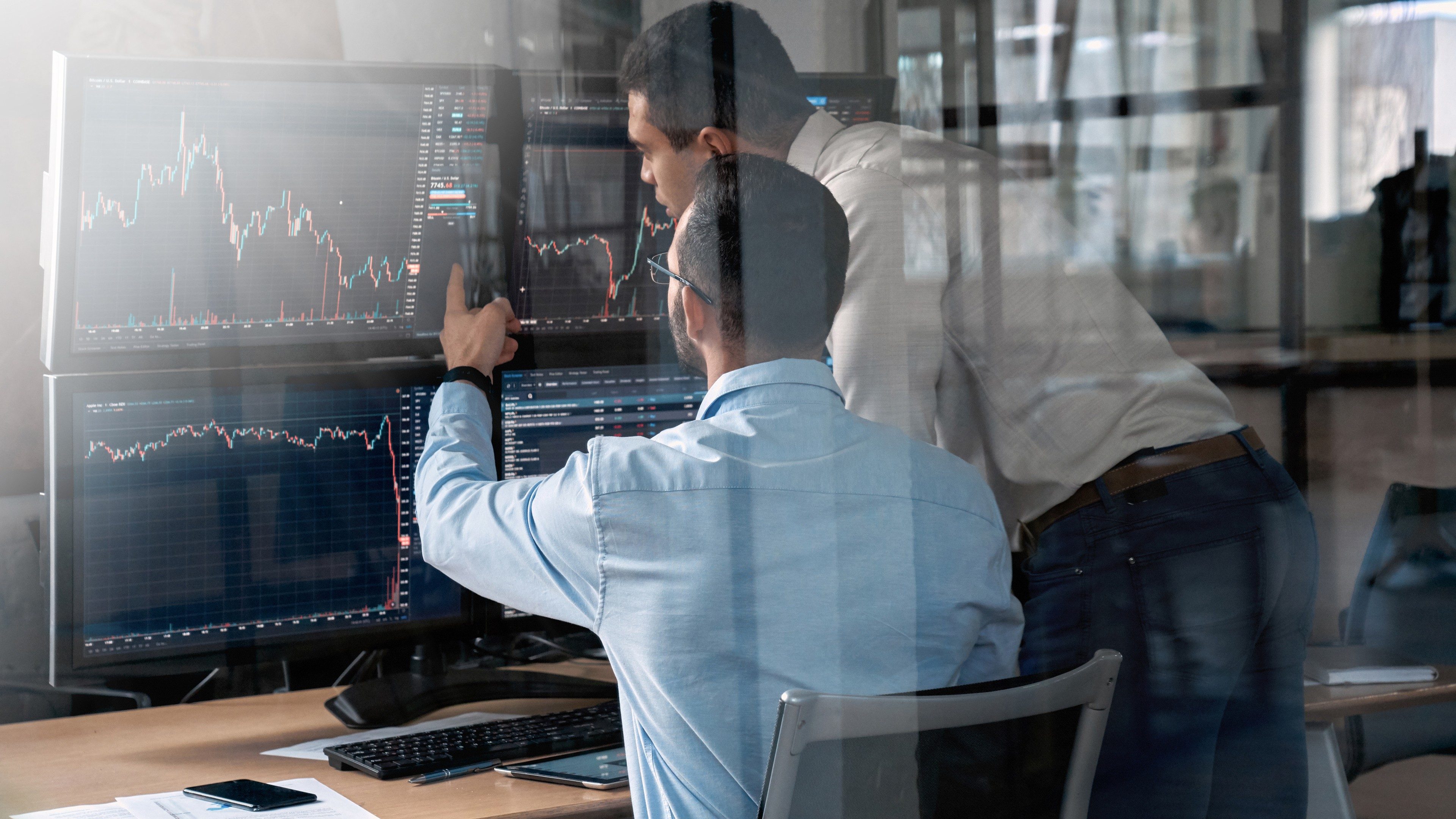 Two businessman working in office together, pointing at screen, discussion and checking global currency index on fund exchange; Shutterstock ID 1806386614; purchase_order: -; job: -; client: -; other: -