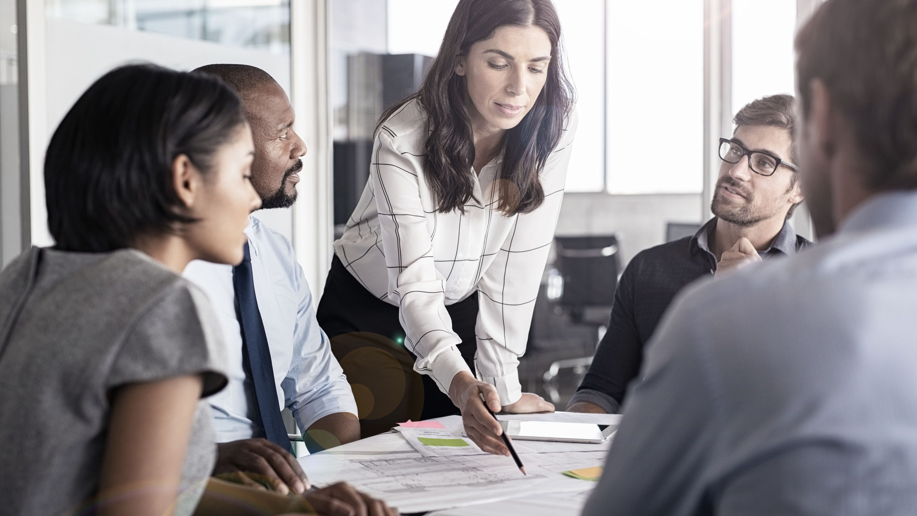 Team of multiethnic architects working on construction plans in meeting room. Engineers and designers discussing project in office. Businesswoman with business team in conference room working on blueprint.