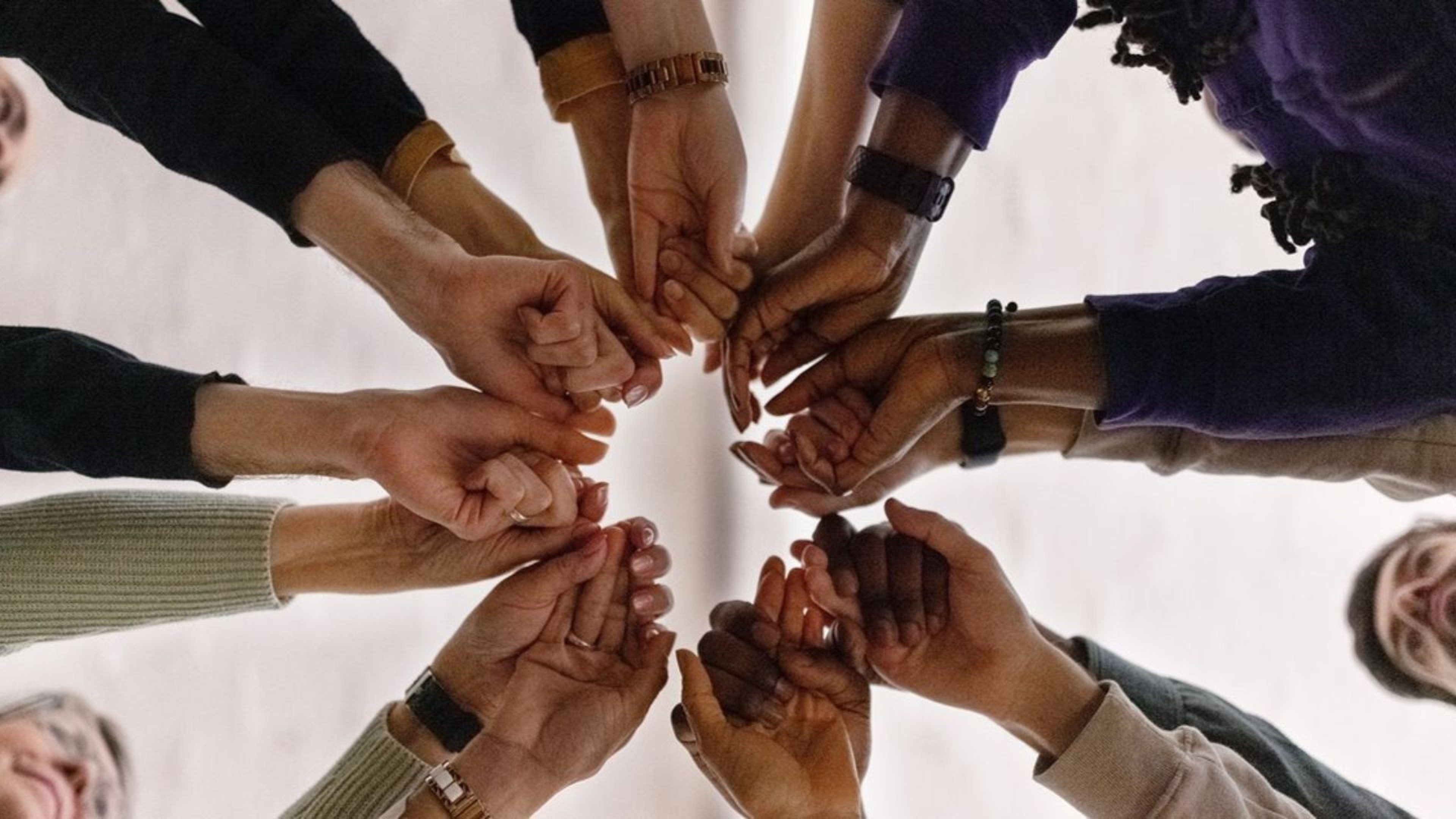 Plusieurs mains de personnes d'origines différentes réunies au centre, symbolisant la solidarité, l'inclusion et la richesse de la mixité chez Swiss Life Asset Managers.