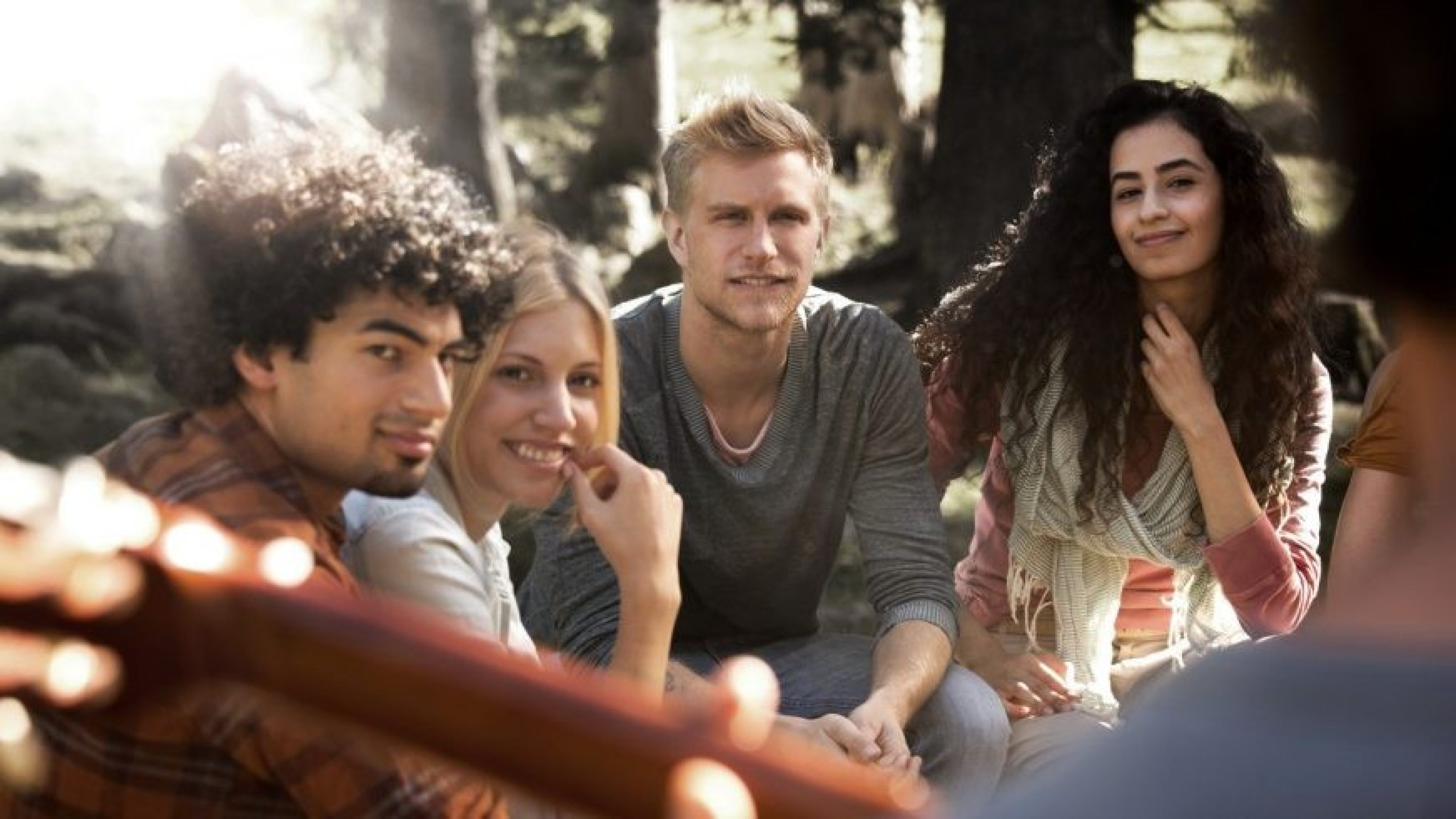 Groupe de quatre jeunes professionnels souriants et décontractés discutant en extérieur, représentant la nouvelle génération de talents et les opportunités internationales.