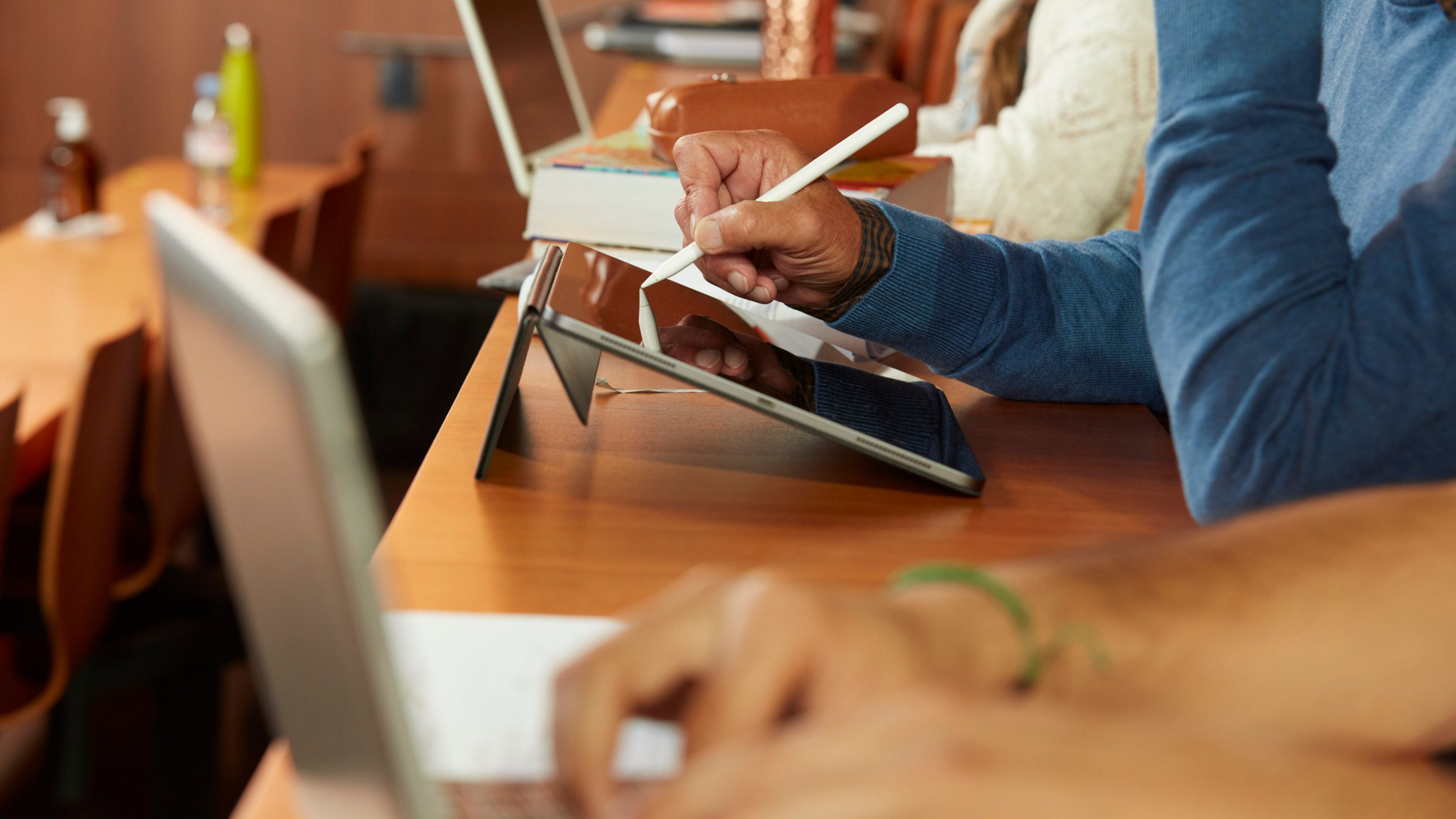 Gros plan sur les mains d'un collaborateur utilisant un stylet sur une tablette numérique, illustrant l'apprentissage continu et la montée en compétences technologiques.