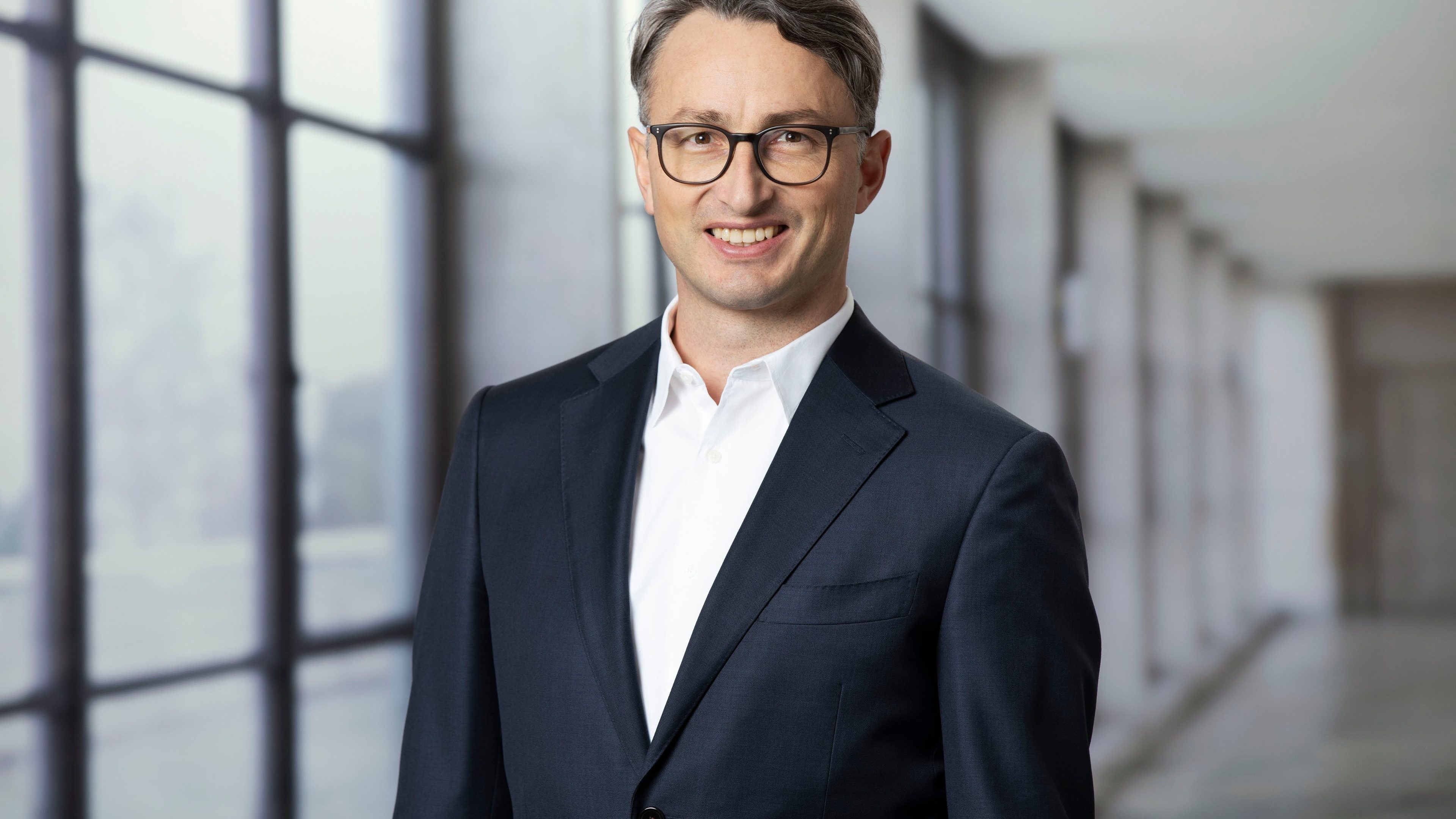 Portrait de Fabian Hürzeler, Président du directoire de Swiss Life Asset Managers France, posant en costume dans un couloir moderne et lumineux.