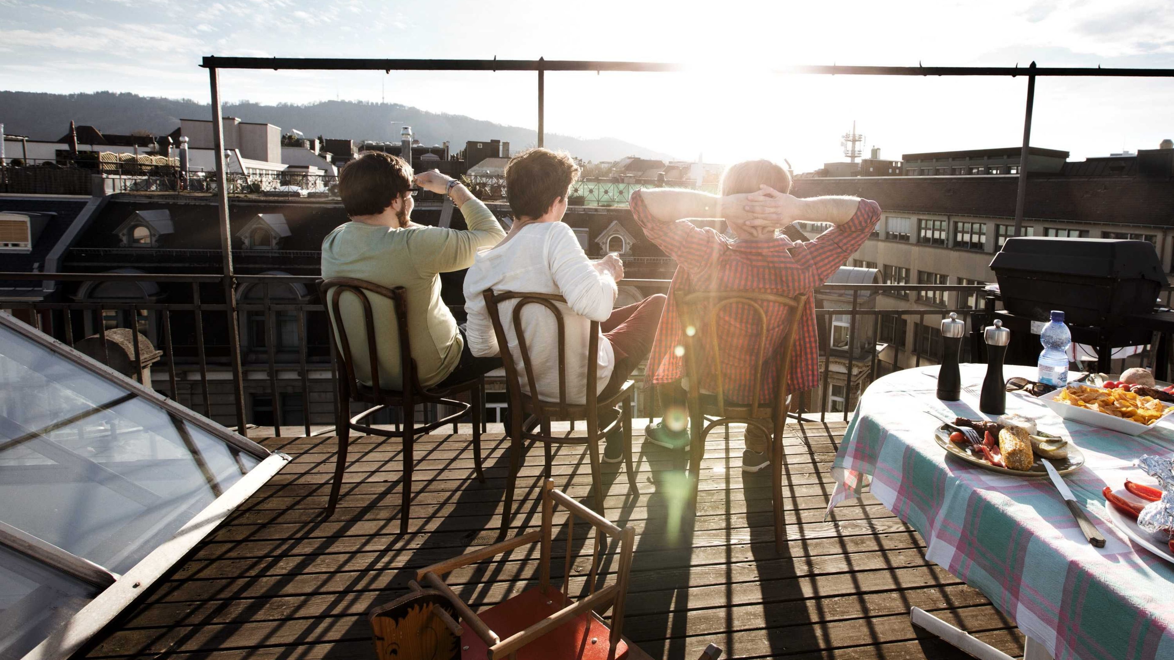 Des gens assis sur une terrasse sur le toit, regardant au loin.