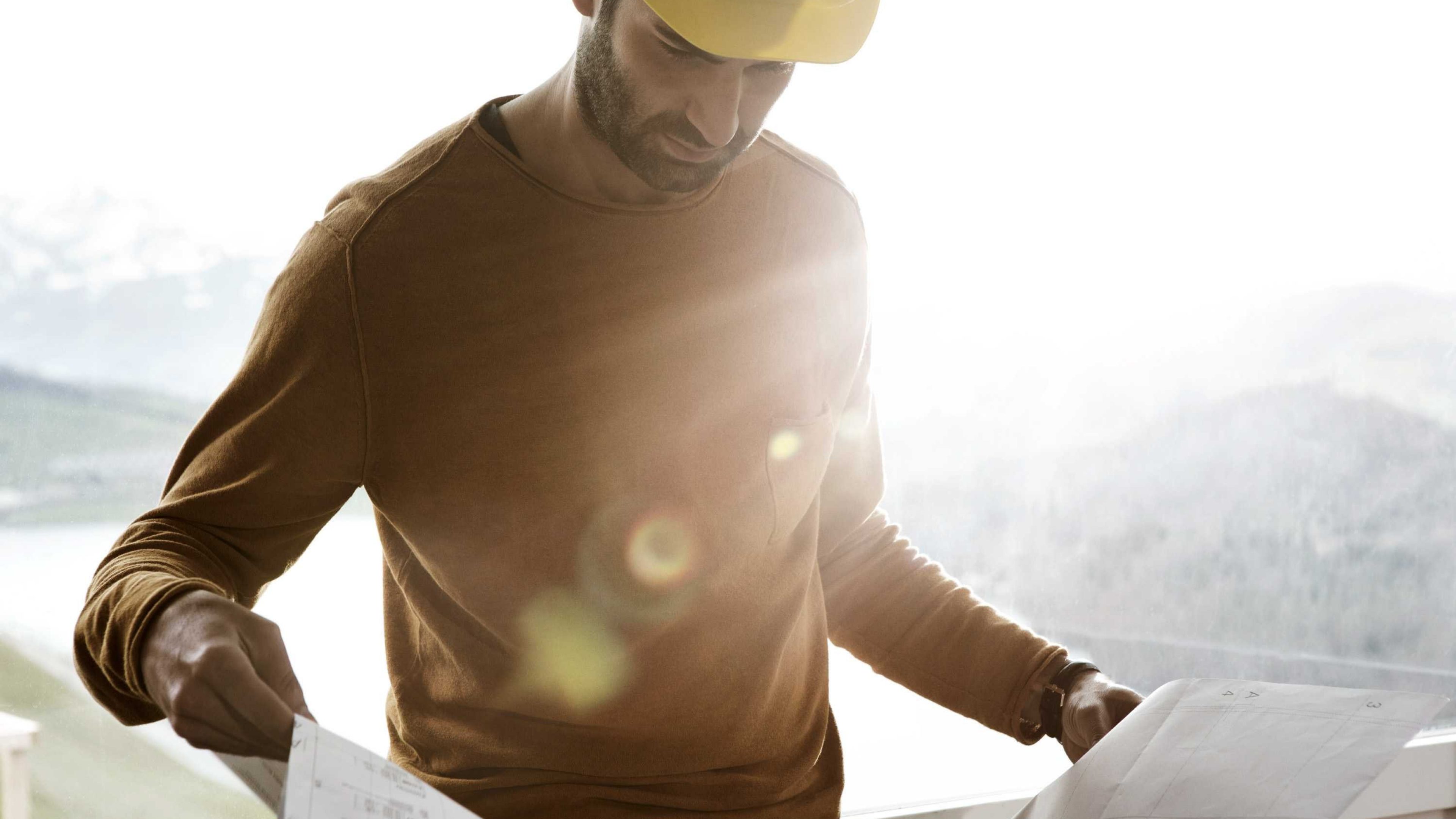 Un homme portant un casque de chantier et regardant un plan de construction.