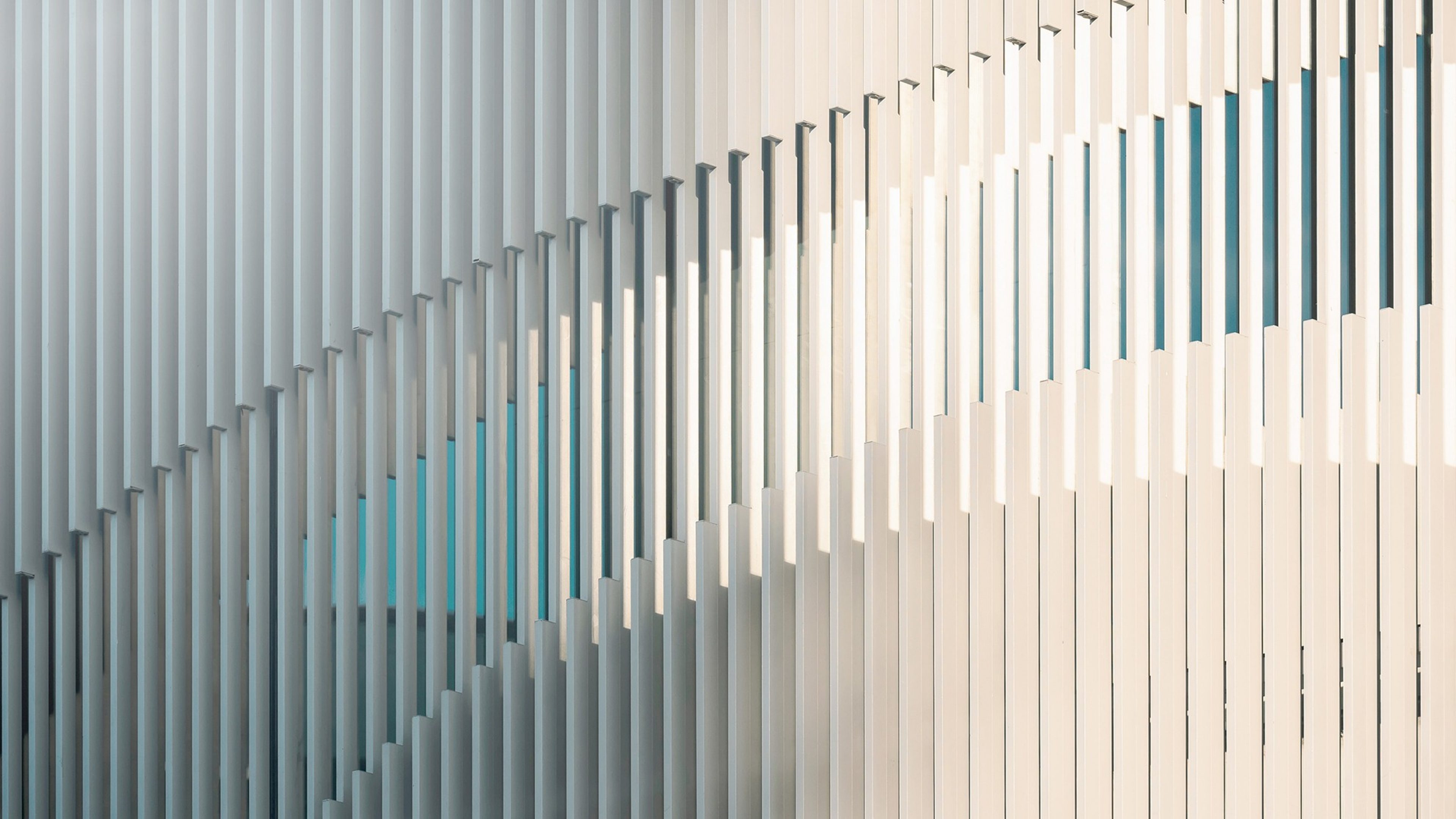 Détail d'une façade de bâtiment contemporain avec des lignes verticales blanches et épurées.