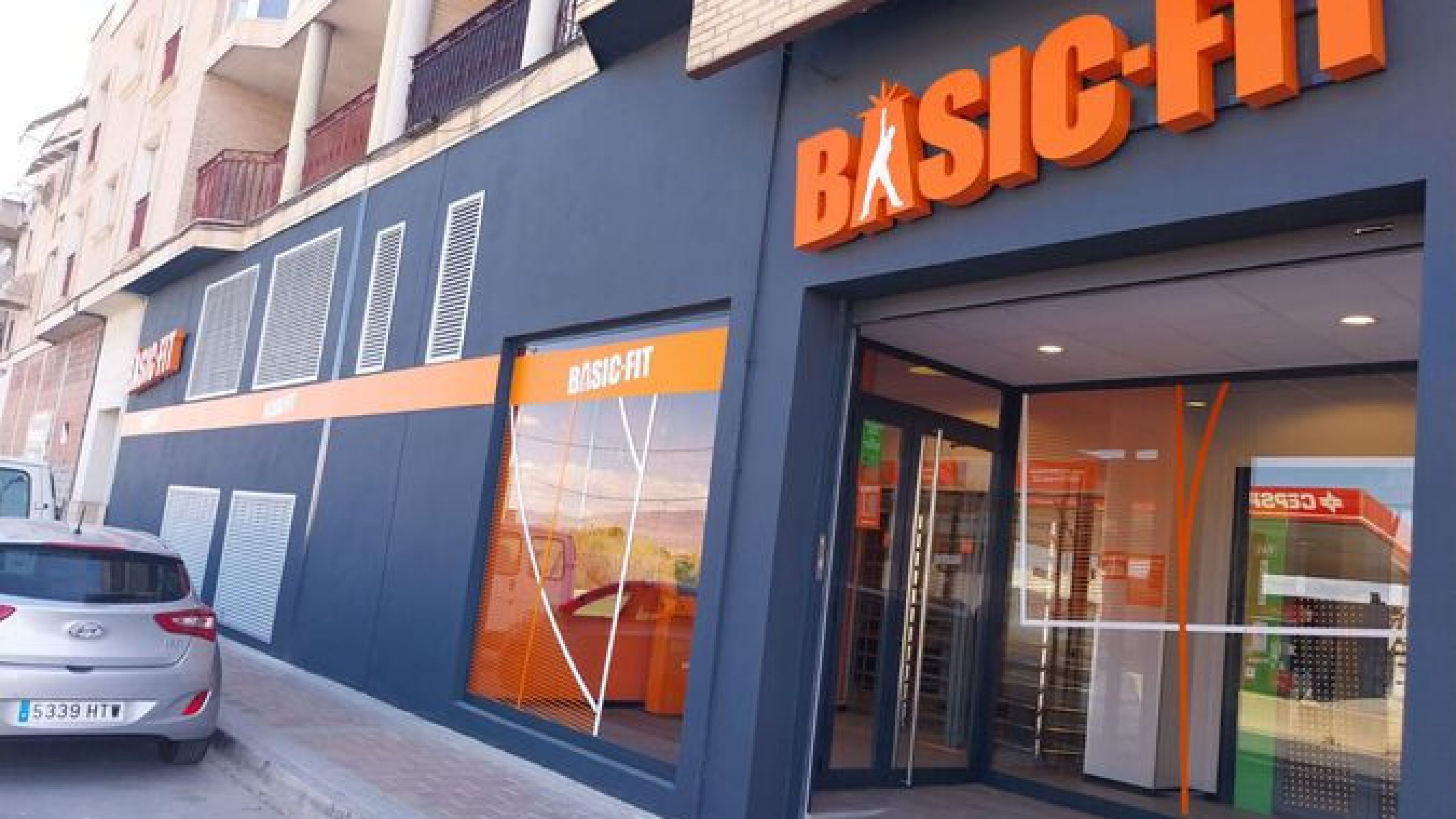 Intérieur d’une salle de sport Basic-Fit en Espagne avec rangées d’haltères, équipements de musculation et espace d’entraînement moderne