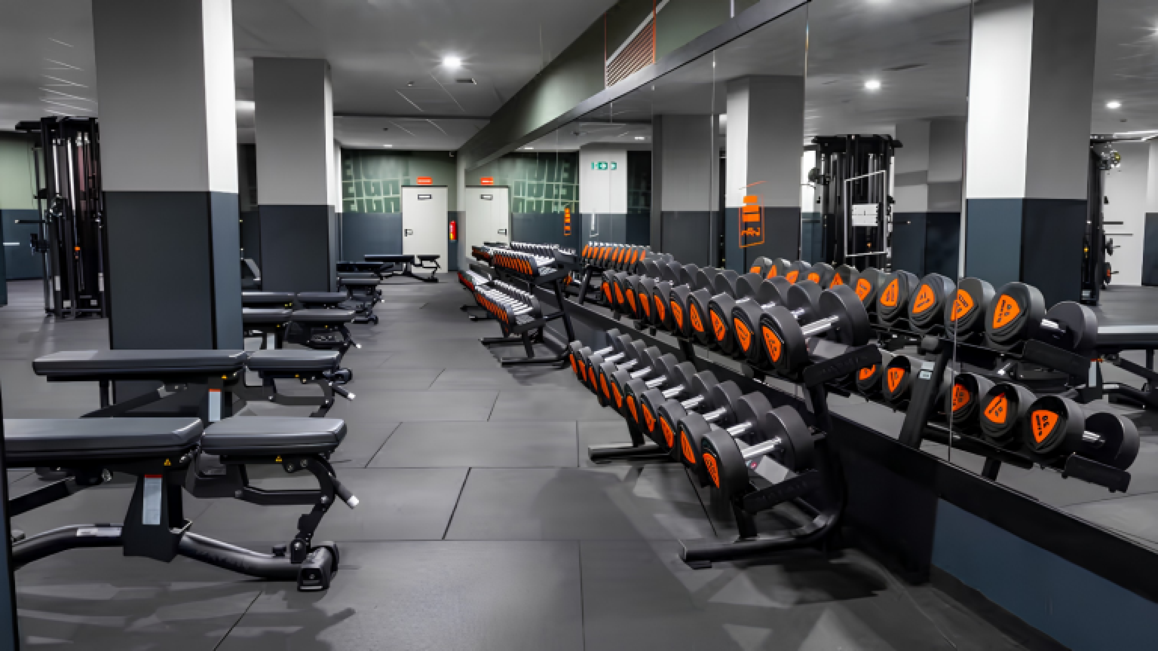 Intérieur d’une salle de sport Basic-Fit en Espagne avec rangées d’haltères, équipements de musculation et espace d’entraînement moderne