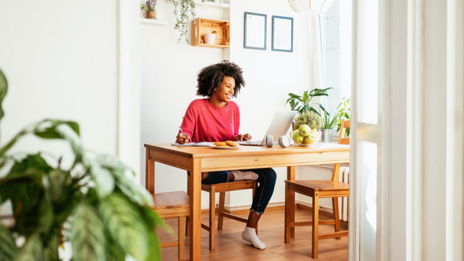 Young African American woman at home, dressed in casual sweater and working or studying.